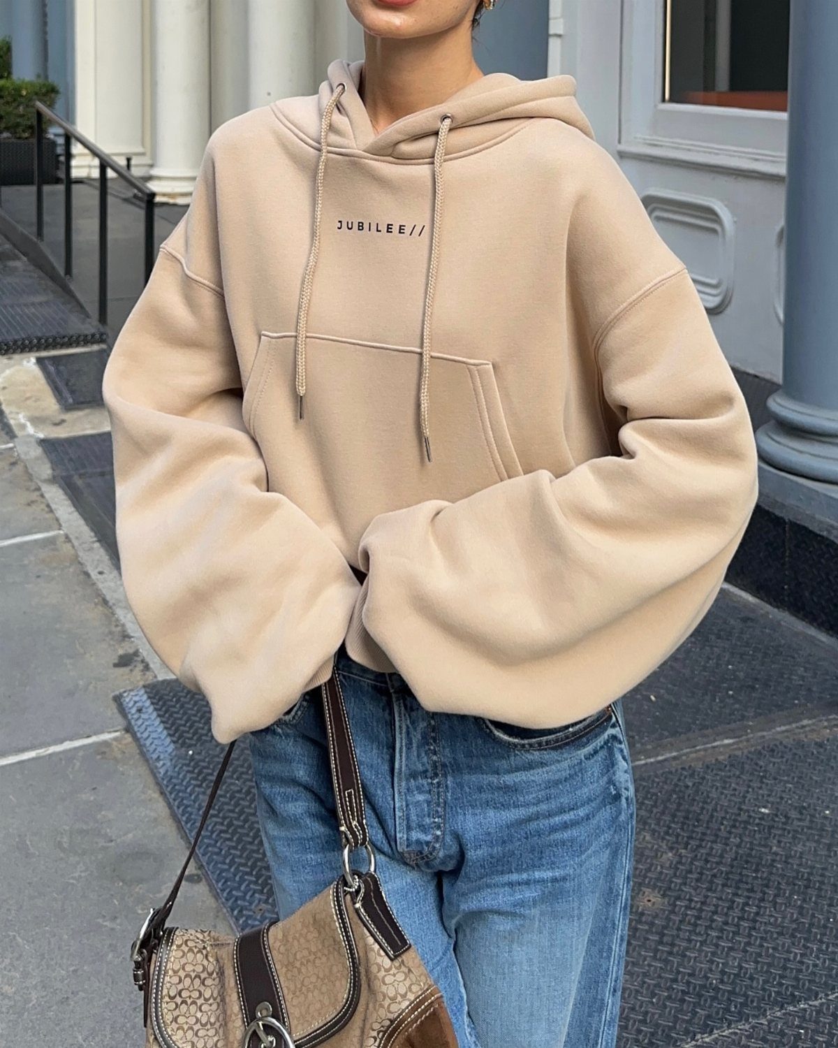 Gender Neutral Outfits: 9 Ideas Anyone Can Wear 3 Beige oversized hoodie and blue jeans with a brown patterned shoulder bag.