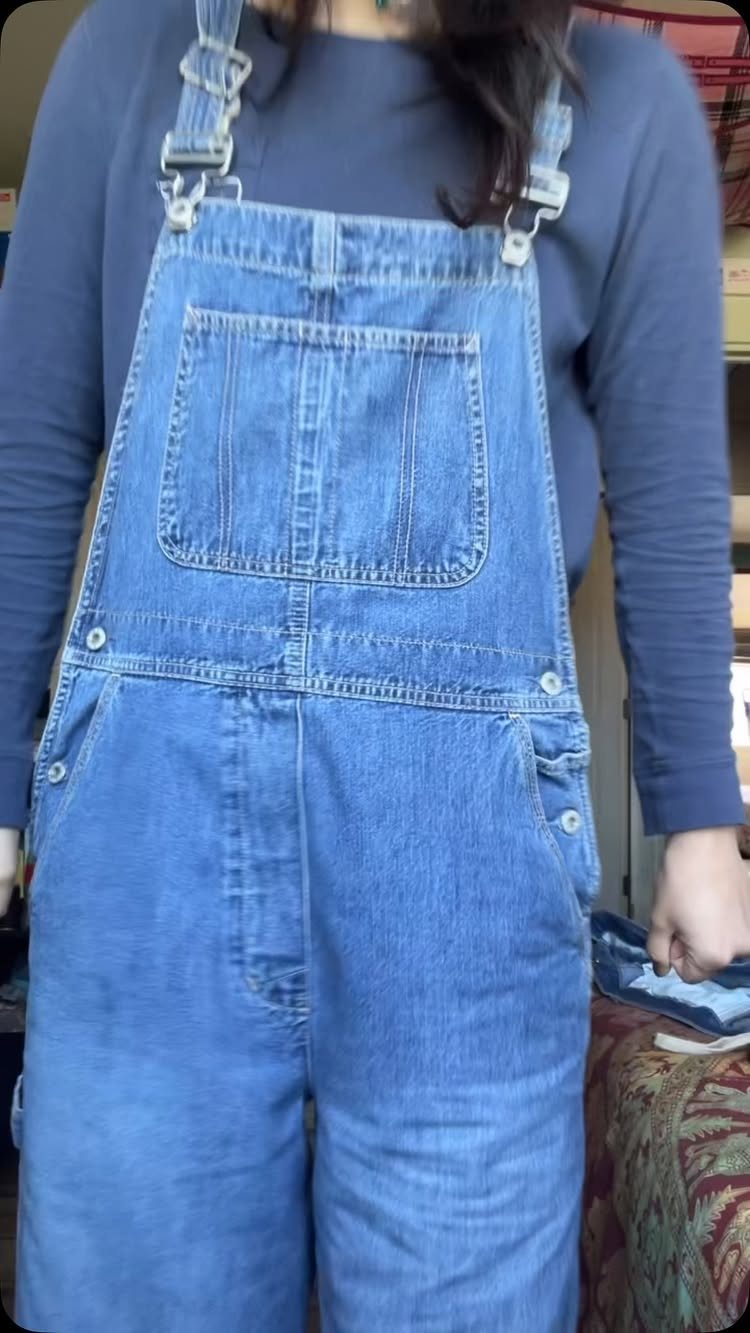 Gender Neutral Outfits: 9 Ideas Anyone Can Wear 6 Blue denim overalls worn over a navy blue long-sleeved shirt.