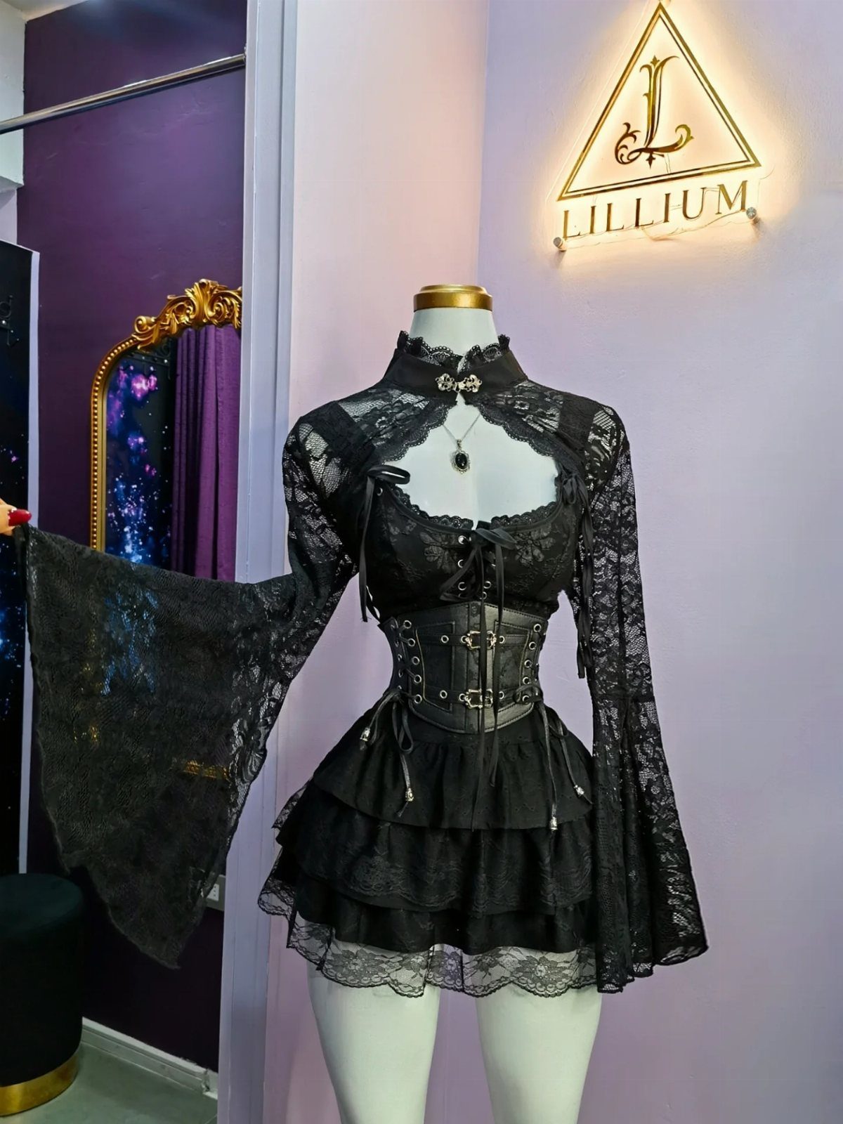 Black gothic three-piece outfit with lace top, corset, and ruffled skirt on mannequin.