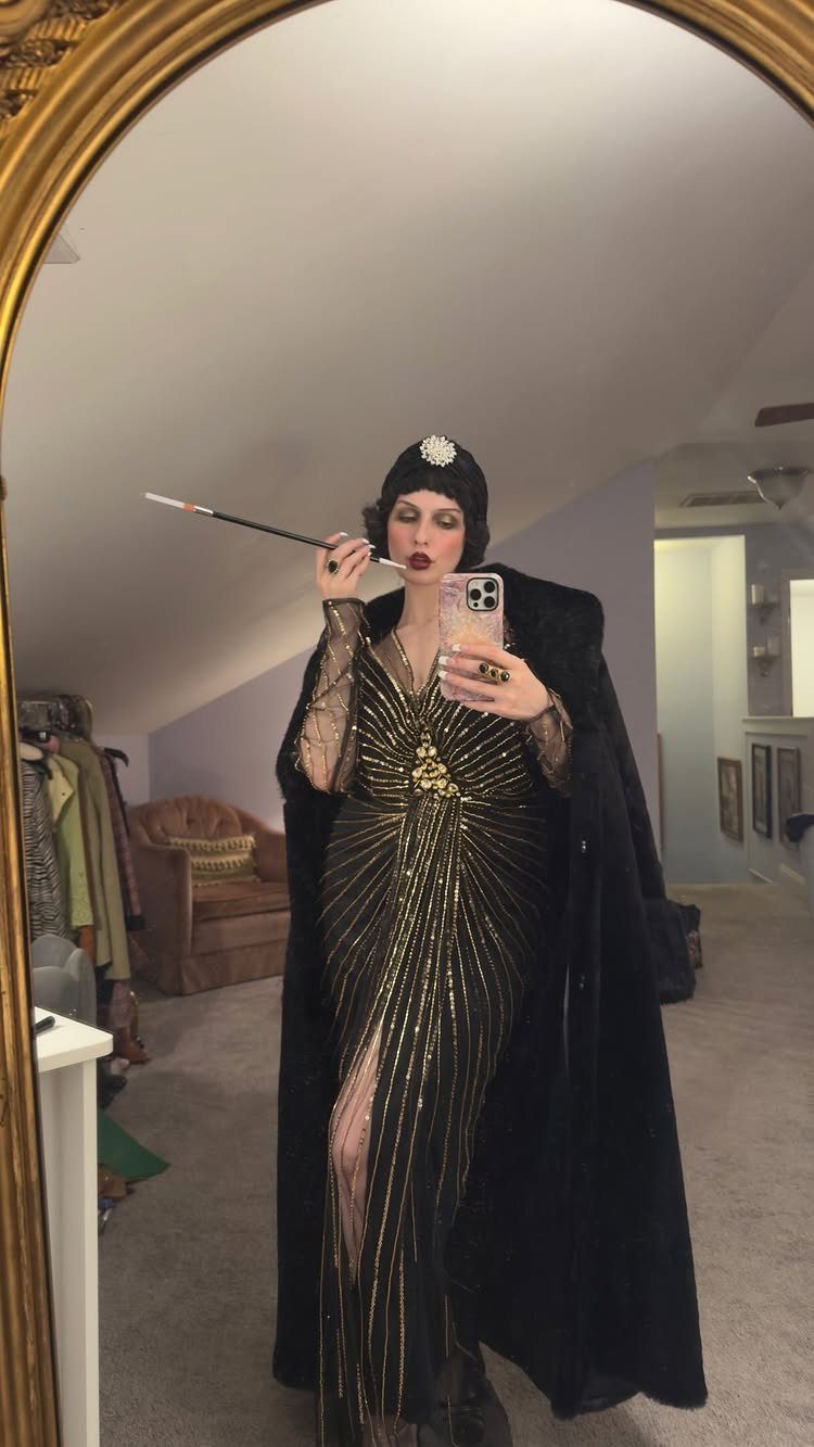 Great Gatsby Themed Outfits: 10 Ideas for Your Next Party 1 Person in a gold beaded flapper dress and black cloak posing in a mirror.