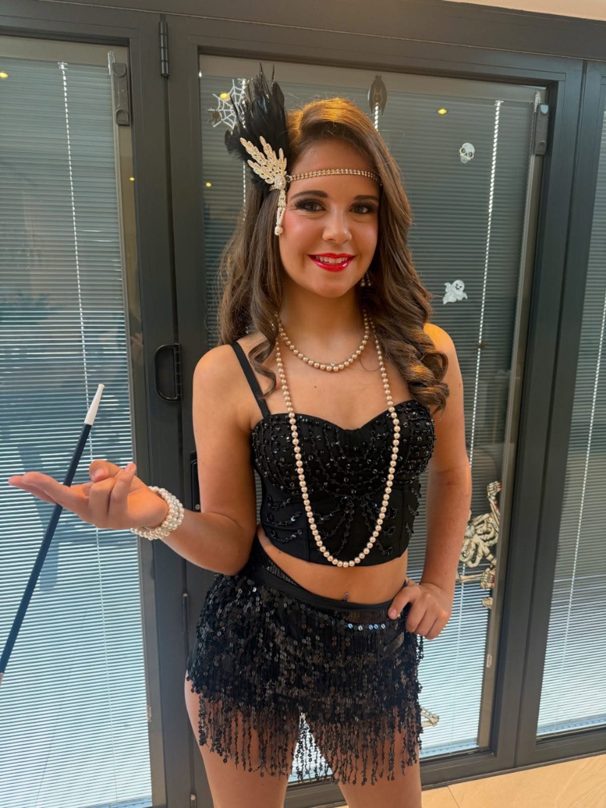 Great Gatsby Themed Outfits: 10 Ideas for Your Next Party 10 Woman in a black sequined flapper outfit with pearls and a feathered headband.