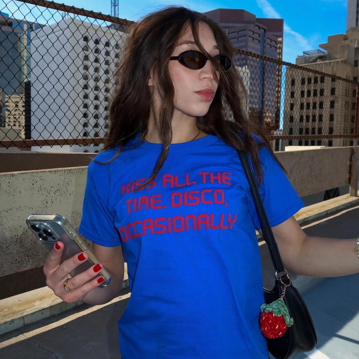 Person wearing a blue graphic baby tee with red text on a rooftop.