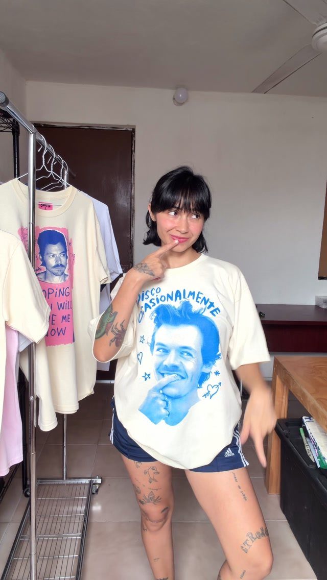 Woman wearing a Harry Styles graphic t-shirt and athletic shorts in a room.