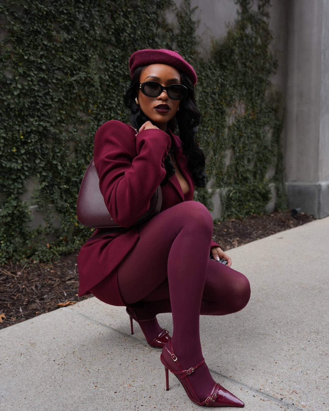 Hilary Banks Outfits: 12 Iconic Looks to Recreate Her Style 4 Woman in burgundy blazer, tights, and beret posing outdoors against ivy wall.