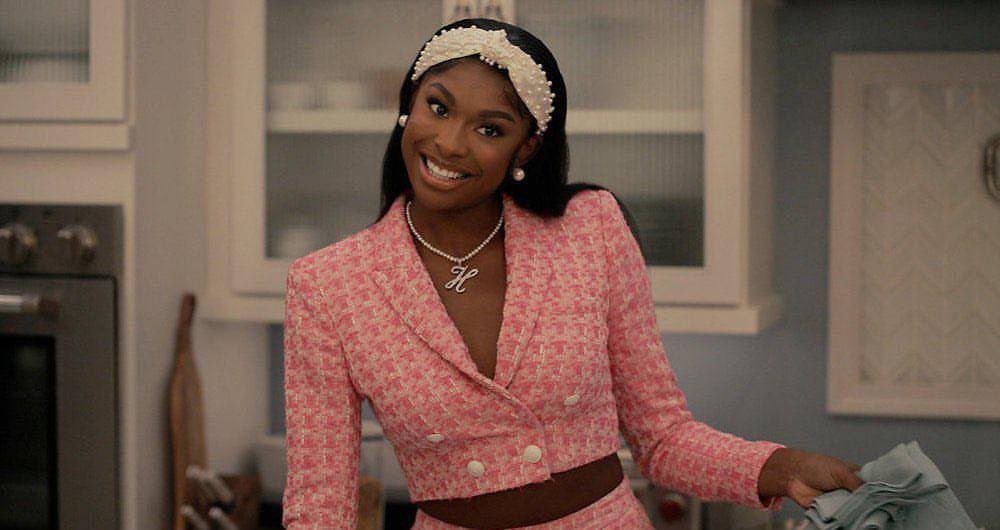 Hilary Banks Outfits: 12 Iconic Looks to Recreate Her Style 5 Woman wearing a pink patterned cropped blazer and matching skirt in a kitchen.
