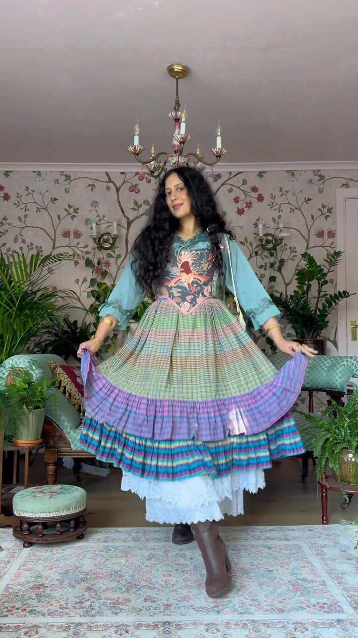 Hunger Games Outfits: 8 Iconic Looks from the Films 4 Woman wearing a colorful tiered floral dress and brown boots in a decorated room.