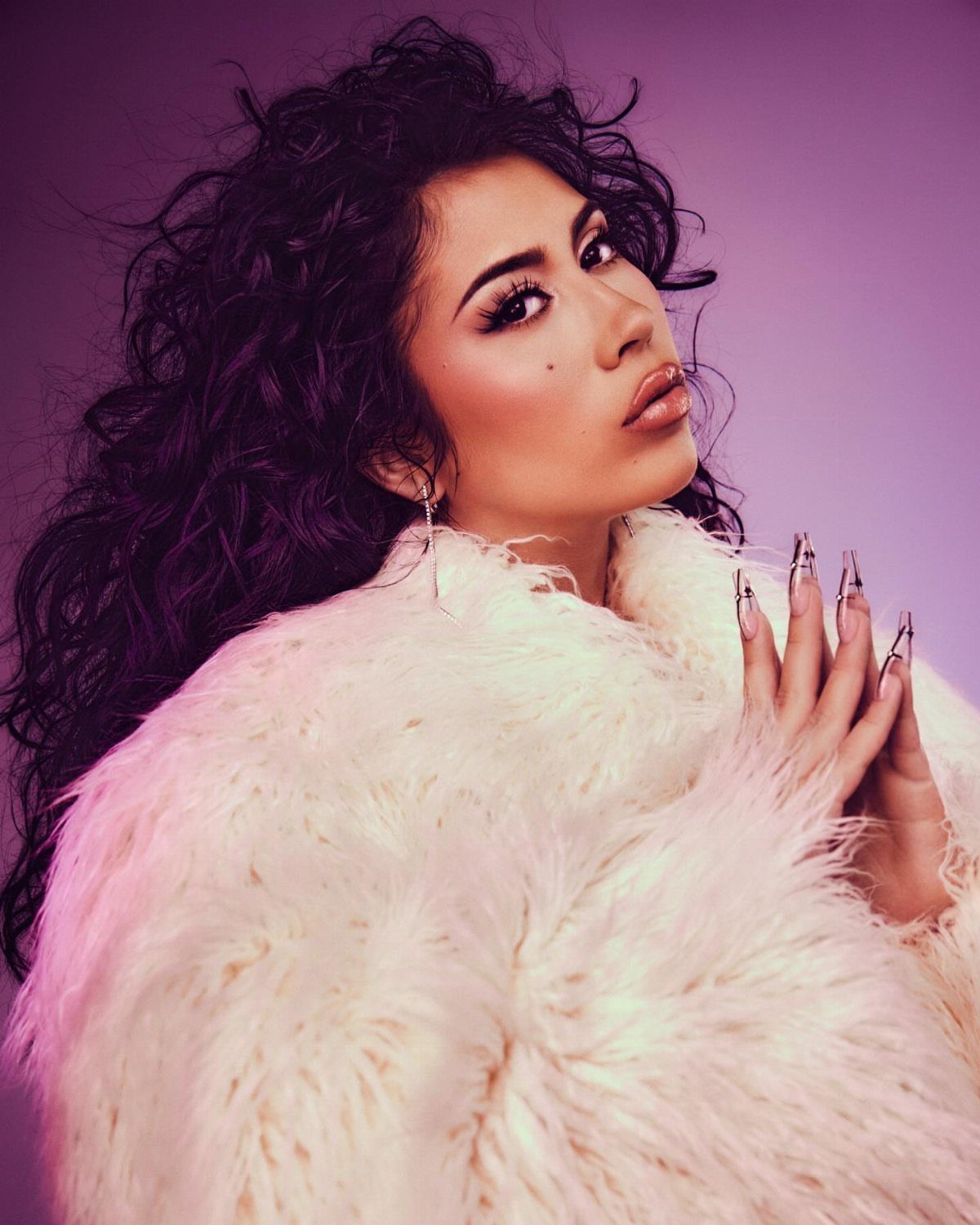Kali Uchis Outfits: 12 Bold Looks for Retro Style 10 Woman with curly hair wearing a white faux-fur coat against a purple background