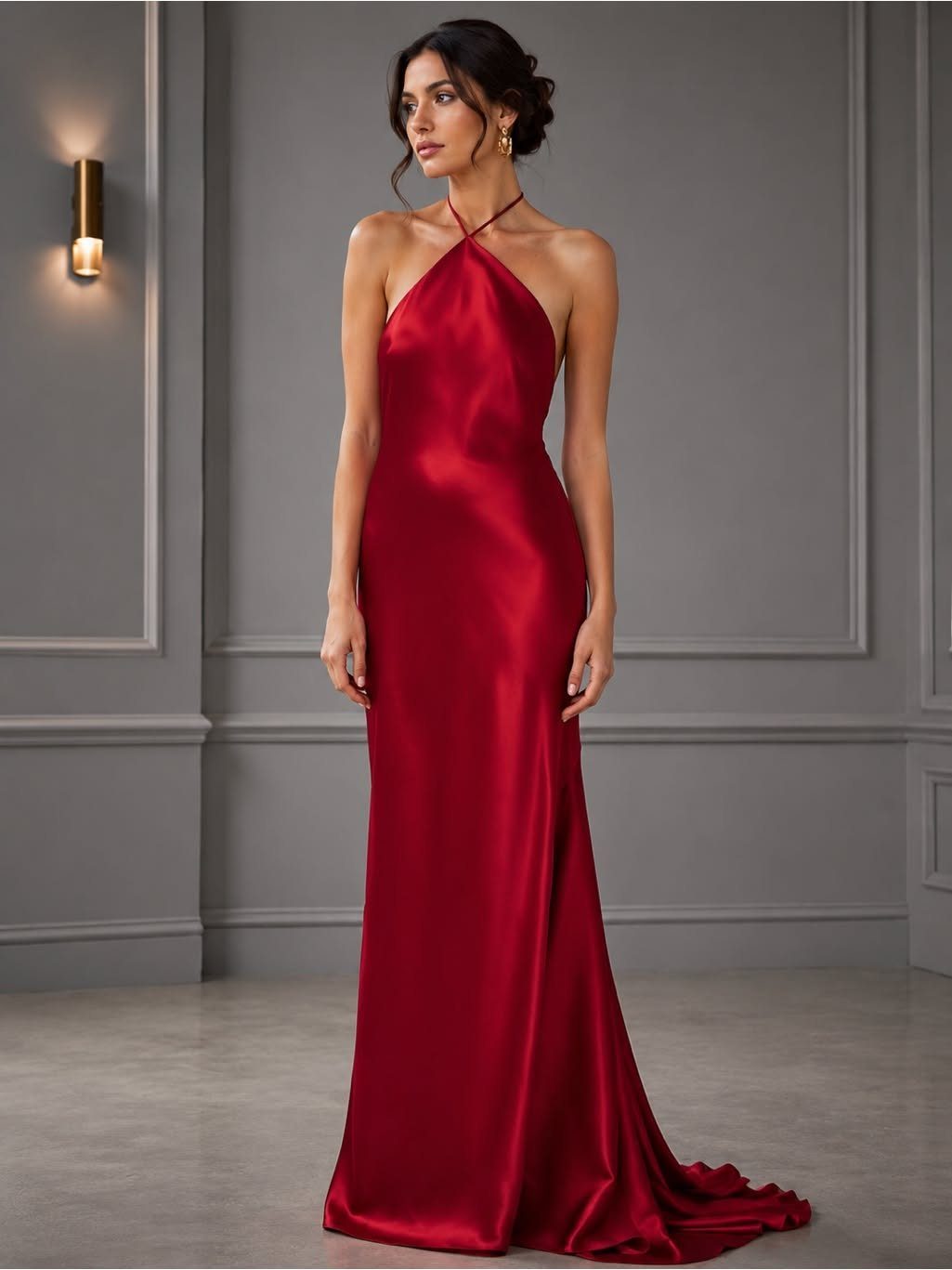 Woman wearing a glamorous floor-length red satin halter-neck gown in a grey room.