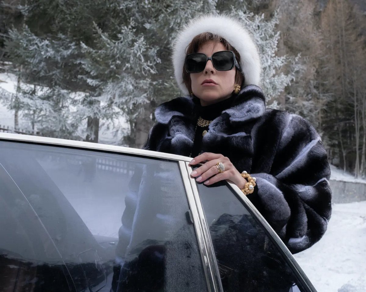 11 Lady Gaga Outfits That Defined Her Style Evolution 6 Lady Gaga in a black fur coat and white hat by a car in snow.