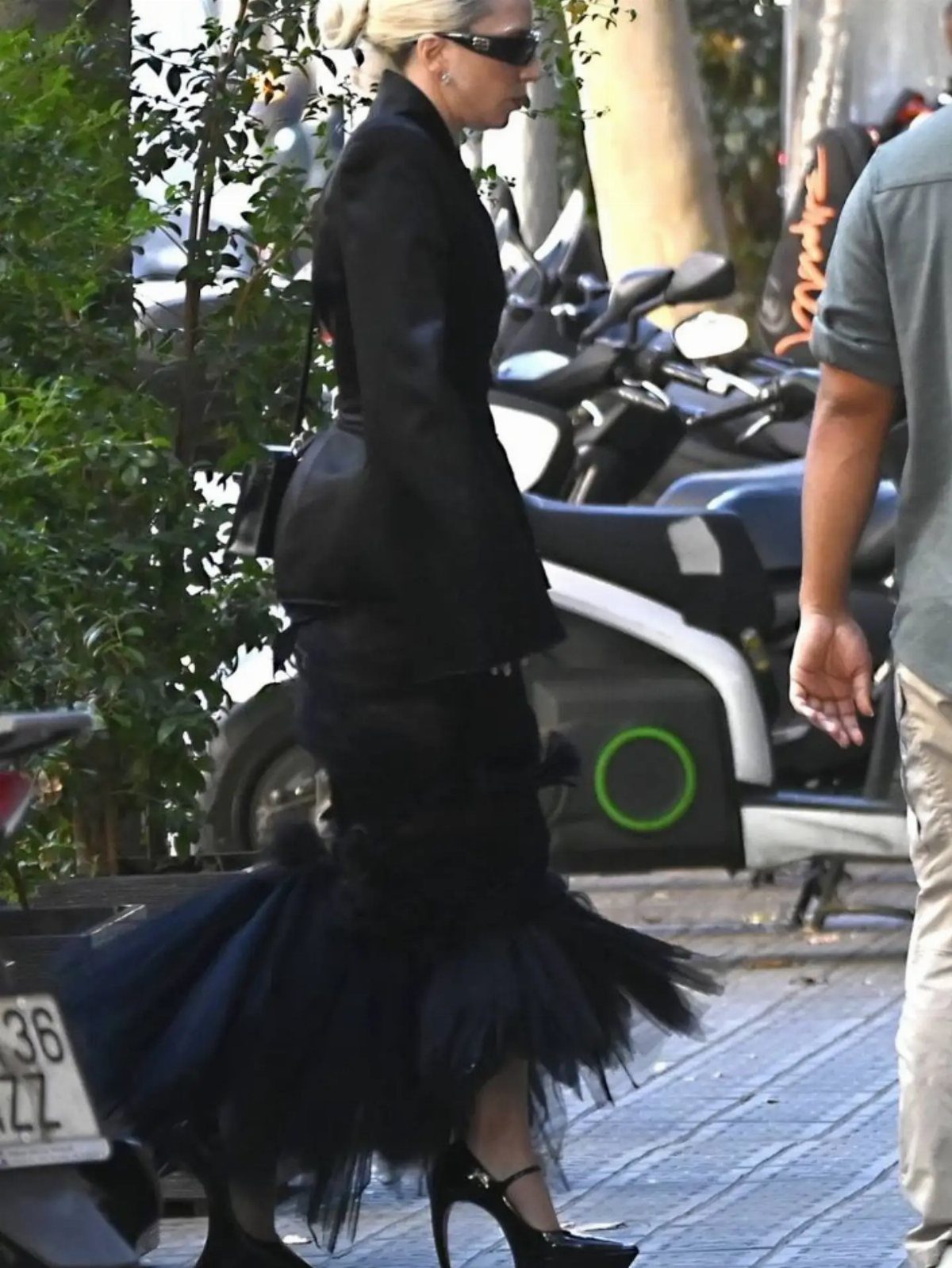 11 Lady Gaga Outfits That Defined Her Style Evolution 7 Lady Gaga wearing a black blazer and voluminous tulle skirt walking on a street.