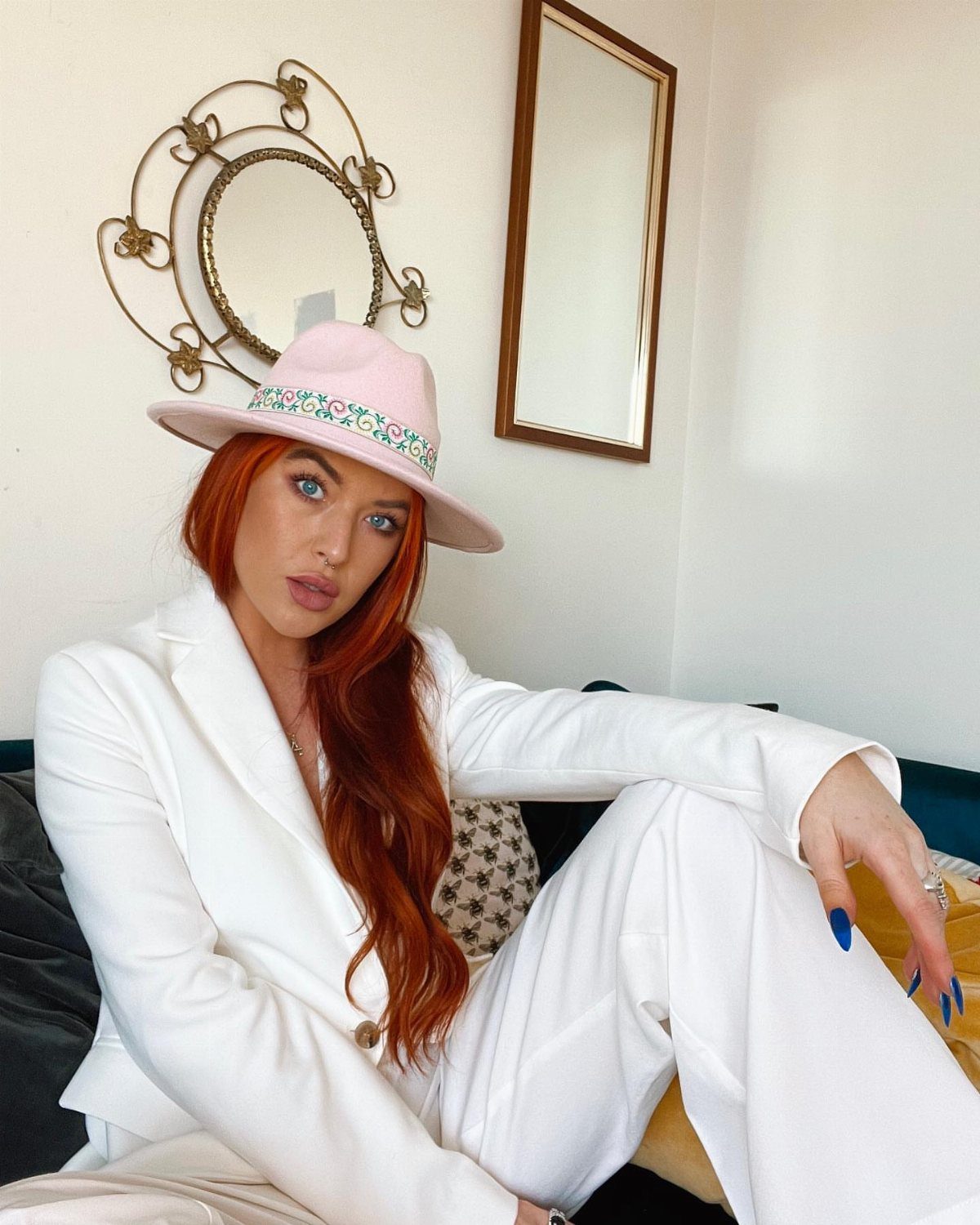 11 Lady Gaga Outfits That Defined Her Style Evolution 1 Woman with red hair wearing a pink wide-brimmed hat and white suit.