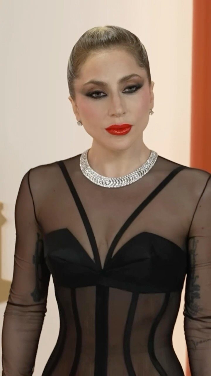 11 Lady Gaga Outfits That Defined Her Style Evolution 11 Lady Gaga in a sheer black gown with a silver collar necklace.