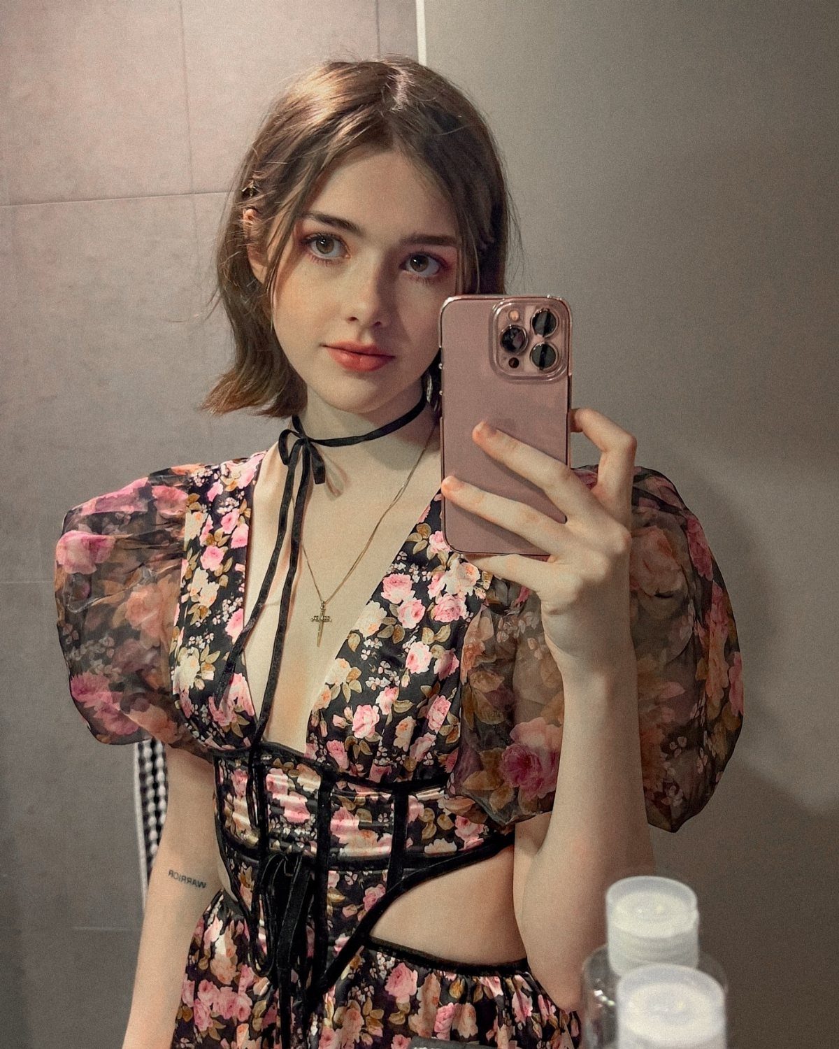 13 Laufey Concert Outfit Ideas for a Whimsical Night Out 10 Young woman in a black floral puff-sleeve dress taking a mirror selfie.