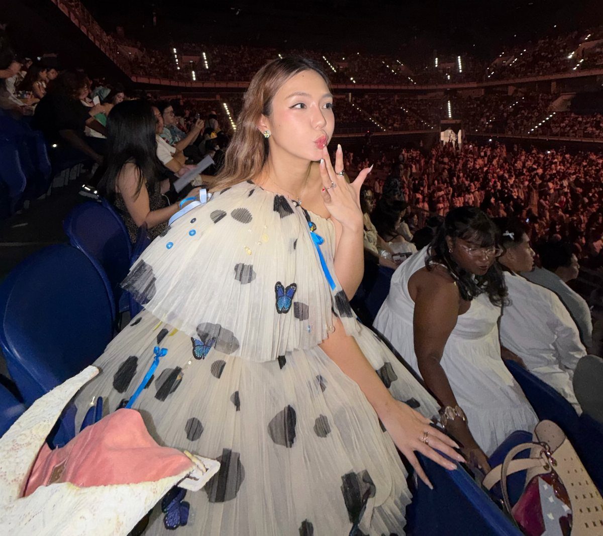 13 Laufey Concert Outfit Ideas for a Whimsical Night Out 1 Woman wearing a voluminous off-white polka dot dress with butterflies at a concert.