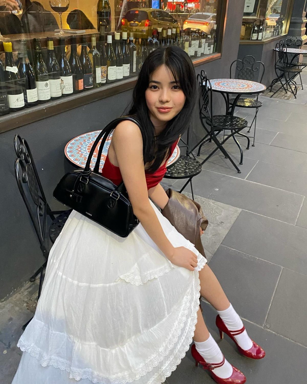 13 Laufey Concert Outfit Ideas for a Whimsical Night Out 4 Woman wearing a red top and white tiered maxi skirt with red Mary Janes.