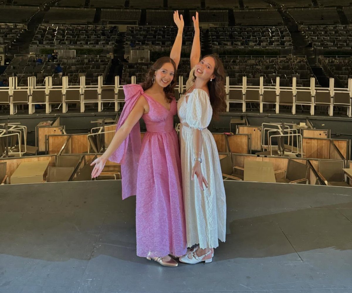 13 Laufey Concert Outfit Ideas for a Whimsical Night Out 2 Two women in pink and white romantic maxi dresses posing on a stage.