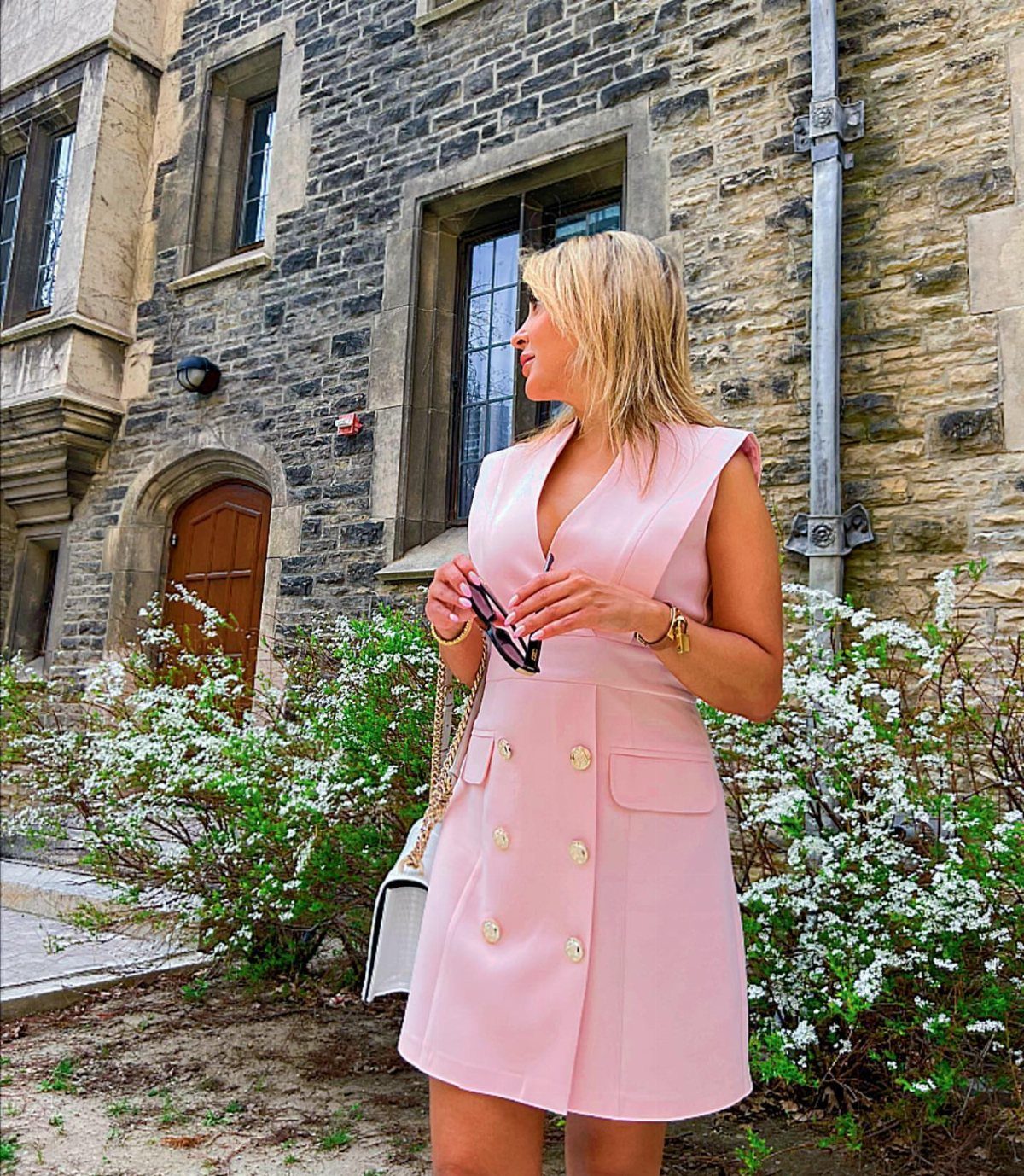10 Legally Blonde Outfits to Channel Elle Woods in 2026 10 Blonde woman in a pink double-breasted mini dress standing by a stone building.
