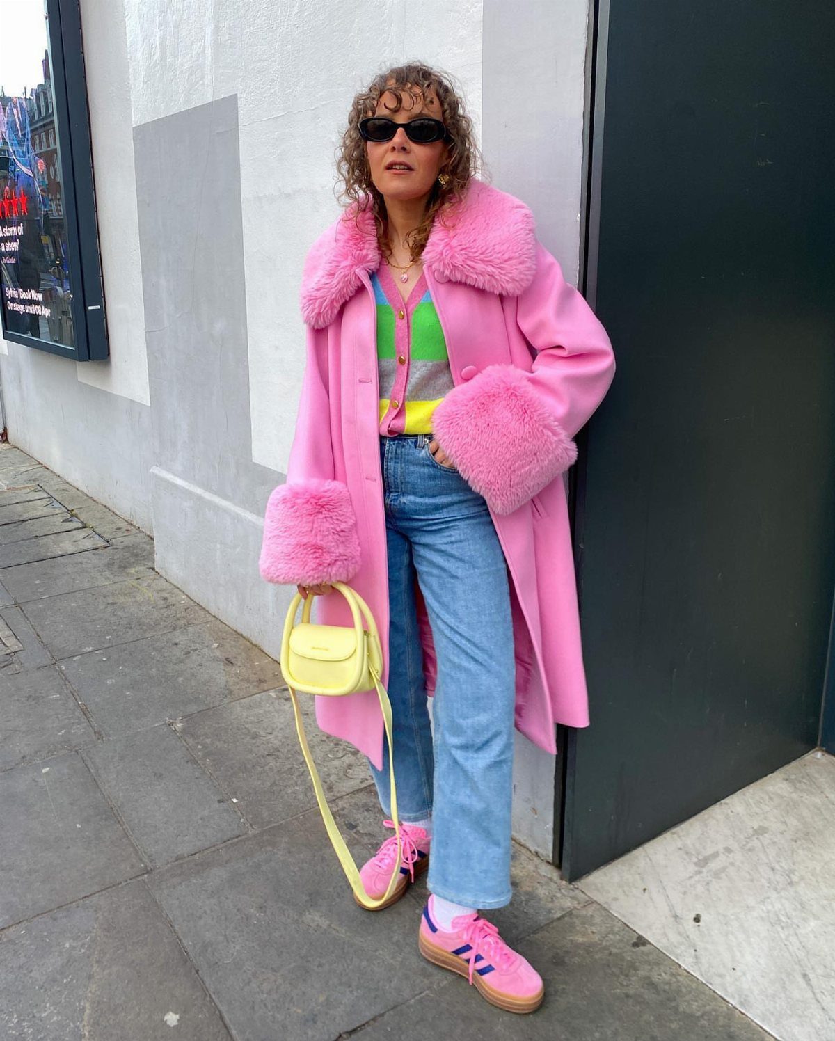 10 Legally Blonde Outfits to Channel Elle Woods in 2026 2 Woman wearing a long pink coat with faux fur trim and blue jeans.