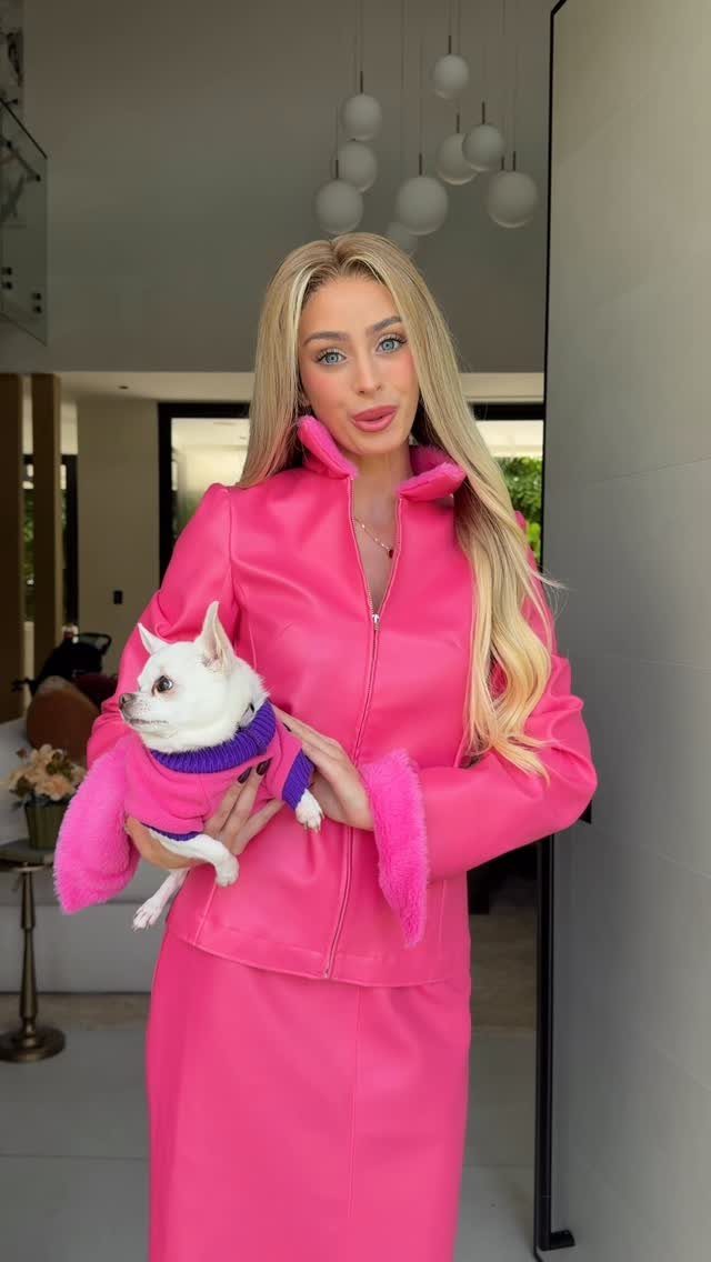 10 Legally Blonde Outfits to Channel Elle Woods in 2026 9 Blonde woman in a bright pink leather jacket and skirt holding a small dog