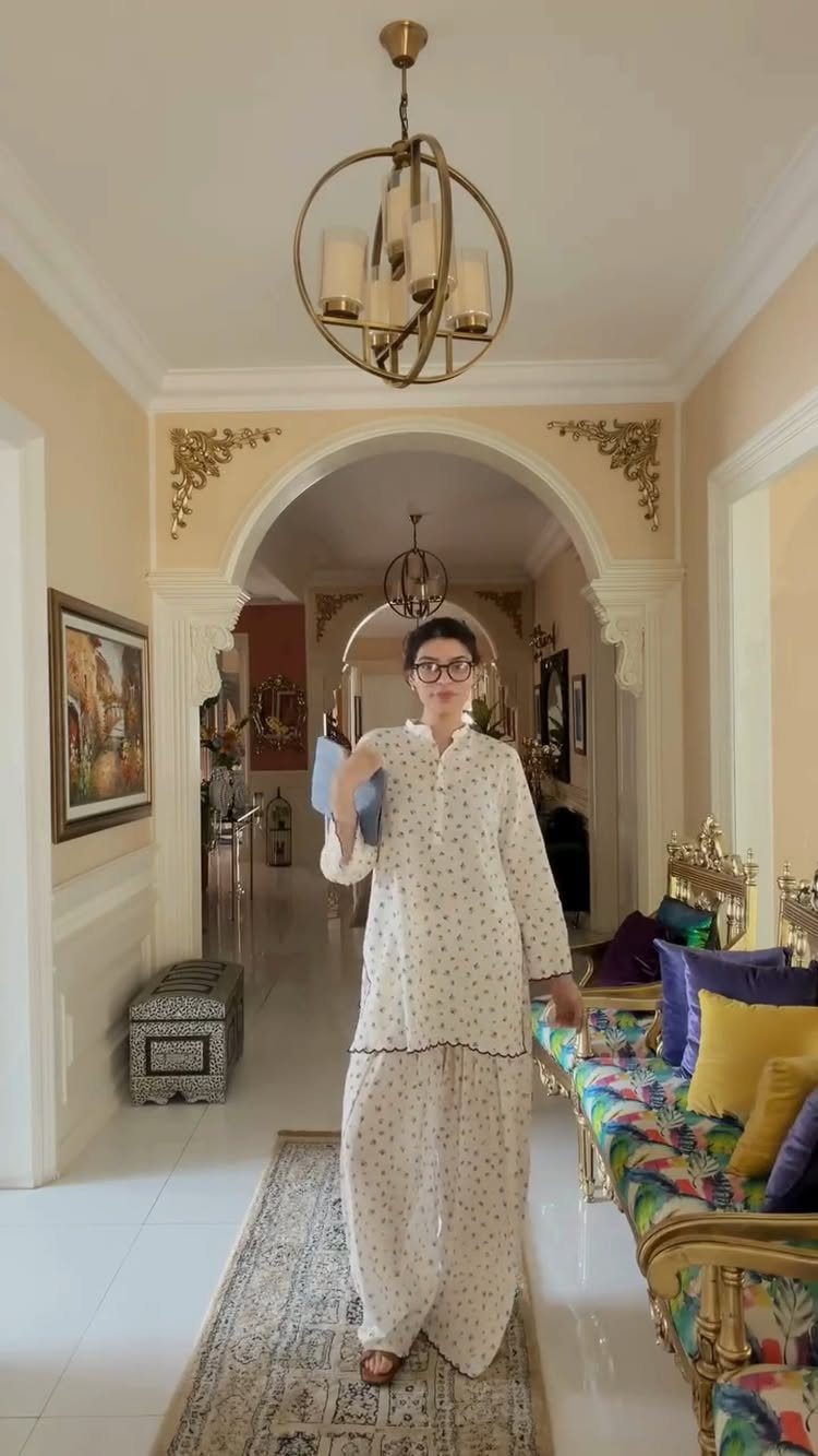 Light Summer Outfits: 8 Fresh Ideas for Cool, Soft Style 1 Woman in a white floral print two-piece outfit standing in an ornate hallway.