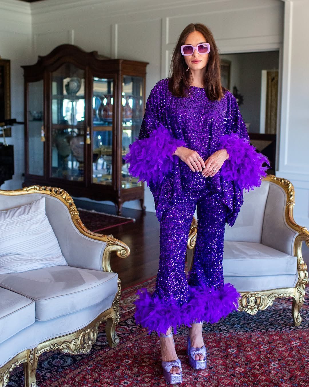 10 Lizzie McGuire Movie Outfits That Defined Y2K Fashion 1 Woman in purple sequined outfit with purple feather trim and pink sunglasses.