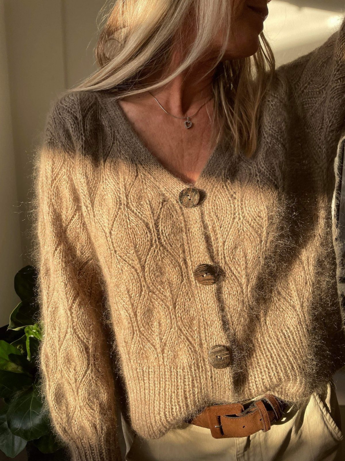 11 Lorelai Gilmore Outfits to Recreate Her Iconic Style 10 Woman wearing a brown cable-knit cardigan with khaki pants and a leather belt.
