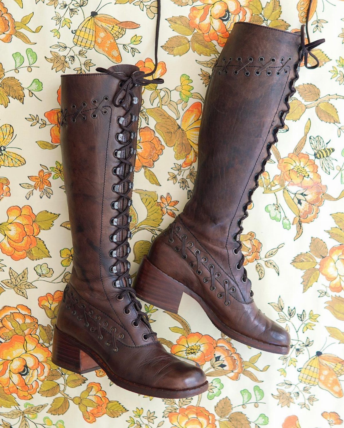 11 Lorelai Gilmore Outfits to Recreate Her Iconic Style 5 Brown leather knee-high lace-up boots with block heels on a floral fabric background.