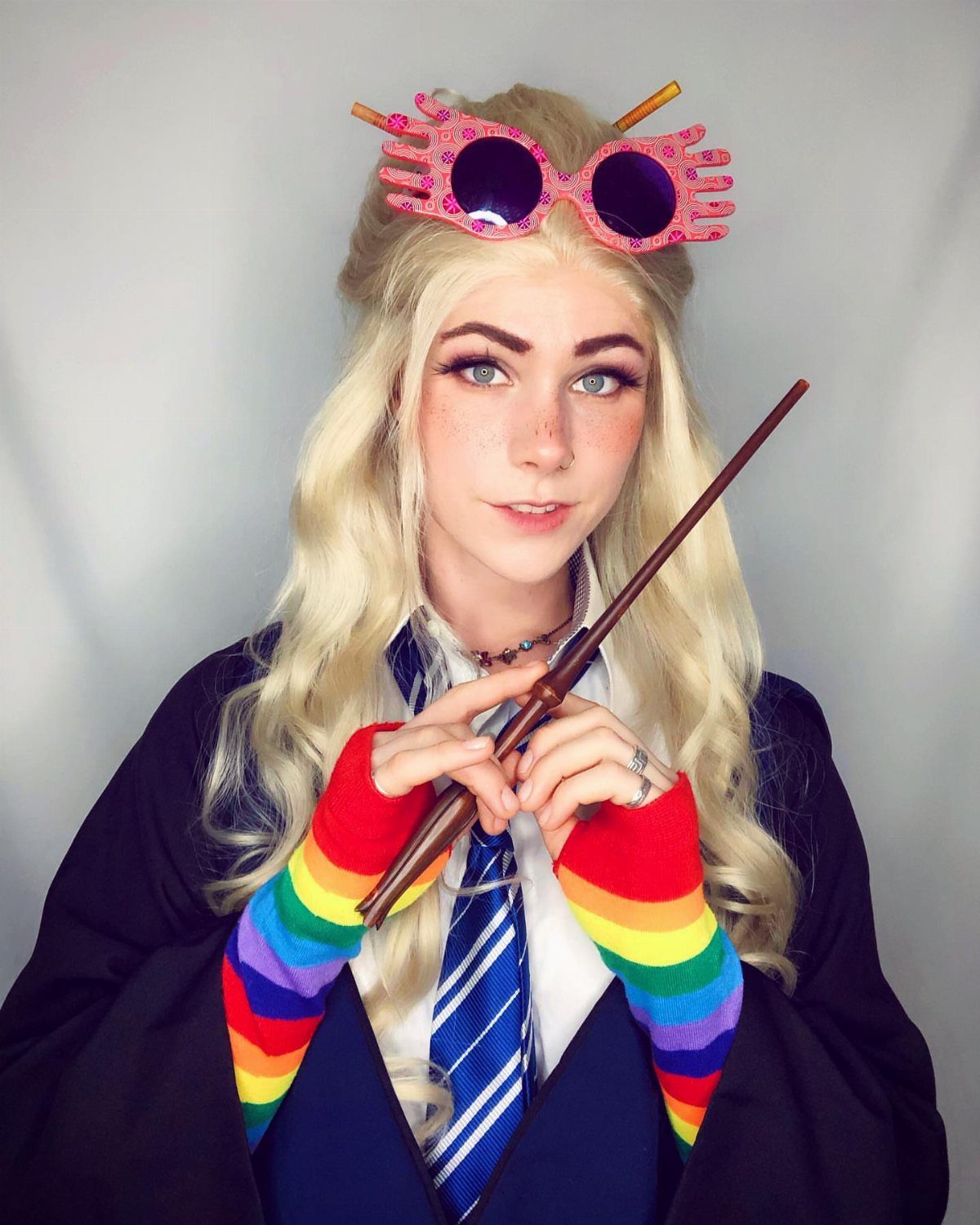 Person dressed as Luna Lovegood wearing Ravenclaw robes, pink glasses, and rainbow sleeves.
