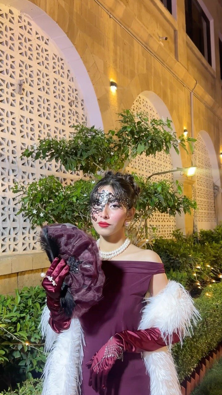 10 Stunning Masquerade Outfits for Women to Wear This Year 8 Woman in burgundy dress and lace masquerade mask posing with a fan and stole.