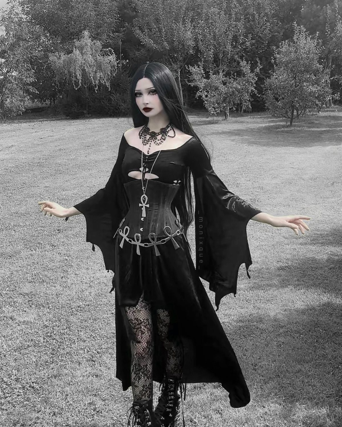 10 Stunning Masquerade Outfits for Women to Wear This Year 3 Woman in black gothic A-line dress with corset bodice and lace tights outdoors.