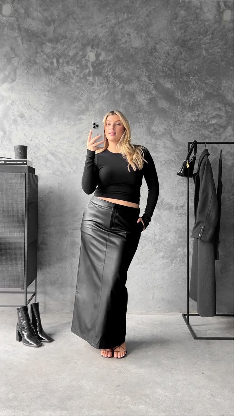 12 Maxi Skirt Outfits to Wear All Year in 2026 8 Woman wearing a black long-sleeved crop top and a black leather maxi skirt.