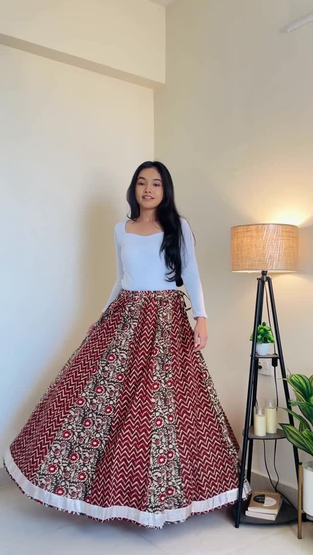 12 Maxi Skirt Outfits to Wear All Year in 2026 6 Woman wearing a white long-sleeved top and a patterned red cotton maxi skirt.