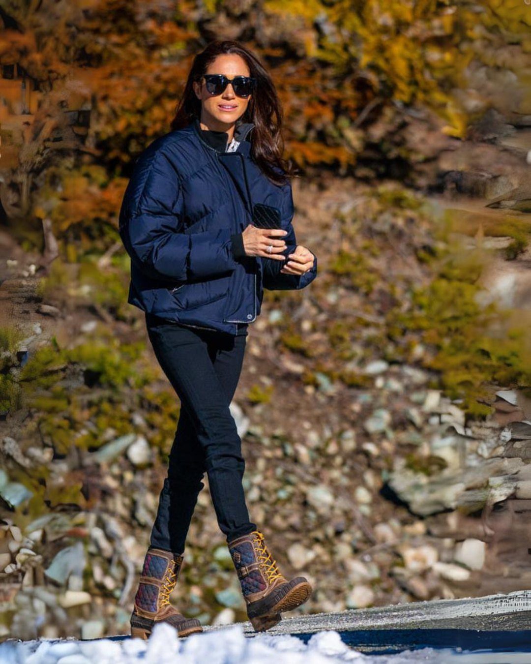 Meghan Markle Outfits: 17 Ideas from Tailored to Casual 8 Meghan Markle wearing a navy puffer jacket, black jeans, and brown winter boots.