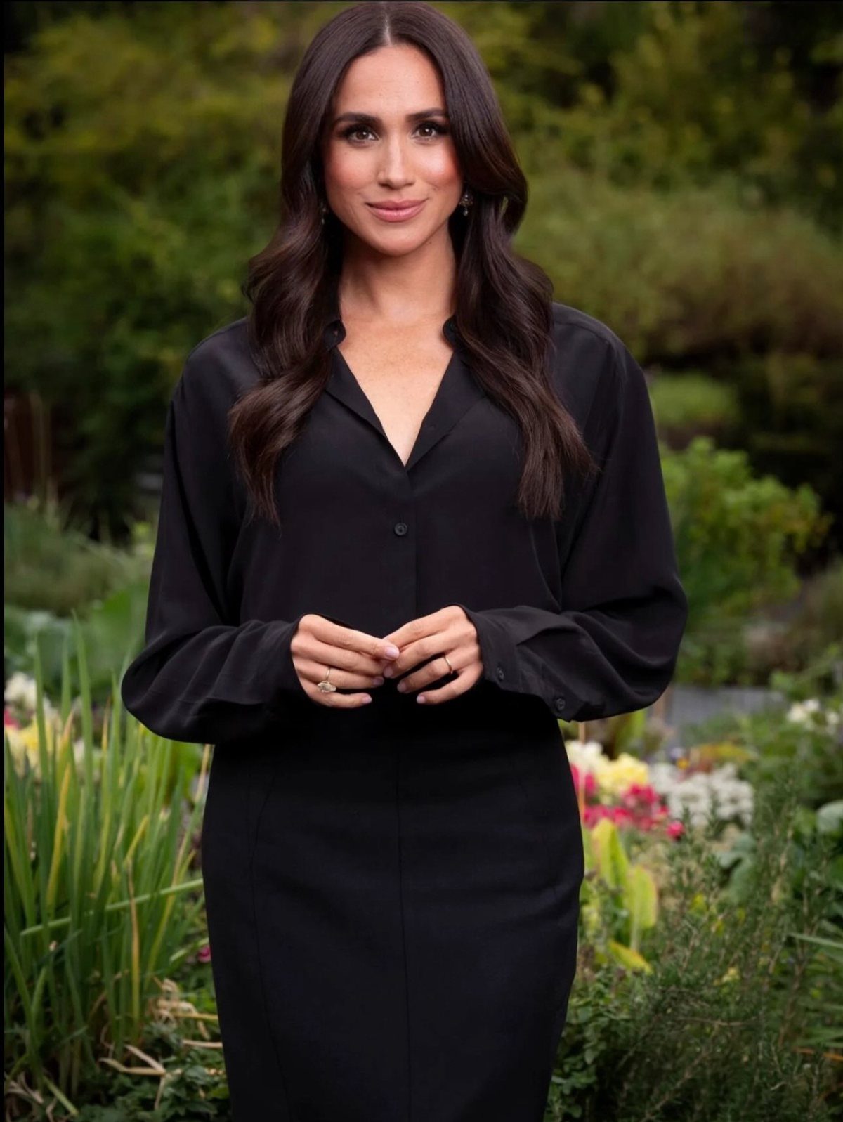 Meghan Markle Outfits: 17 Ideas from Tailored to Casual 4 Meghan Markle wearing a long-sleeved black shirt dress in a lush garden setting.