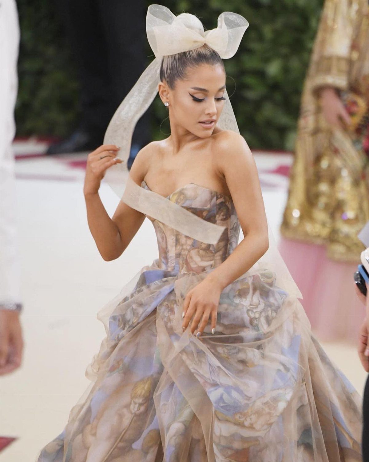 Met Gala Outfits 2026: 10 Looks That Stole the Night 8 Woman in a voluminous classical art print gown with a large hair bow.