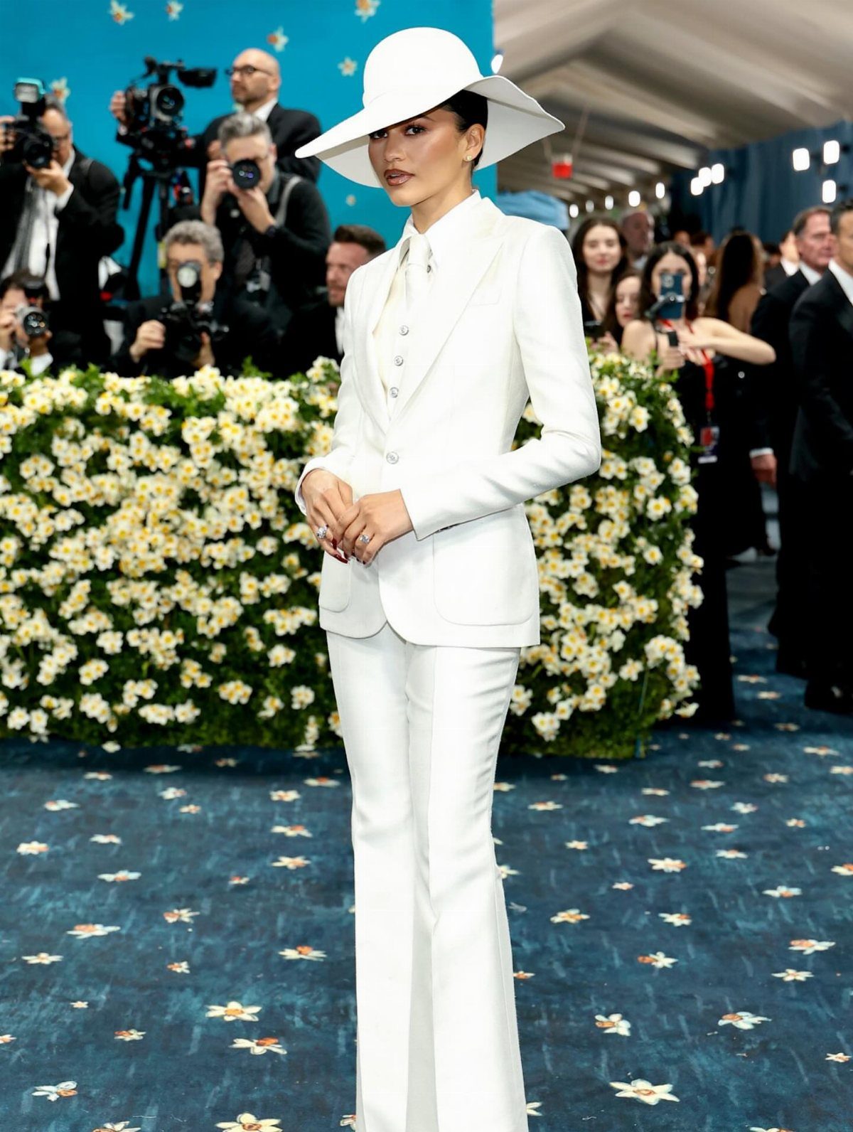 Met Gala Outfits 2026: 10 Looks That Stole the Night 1 Zendaya in a white tailored suit and wide-brimmed hat on a blue carpet.