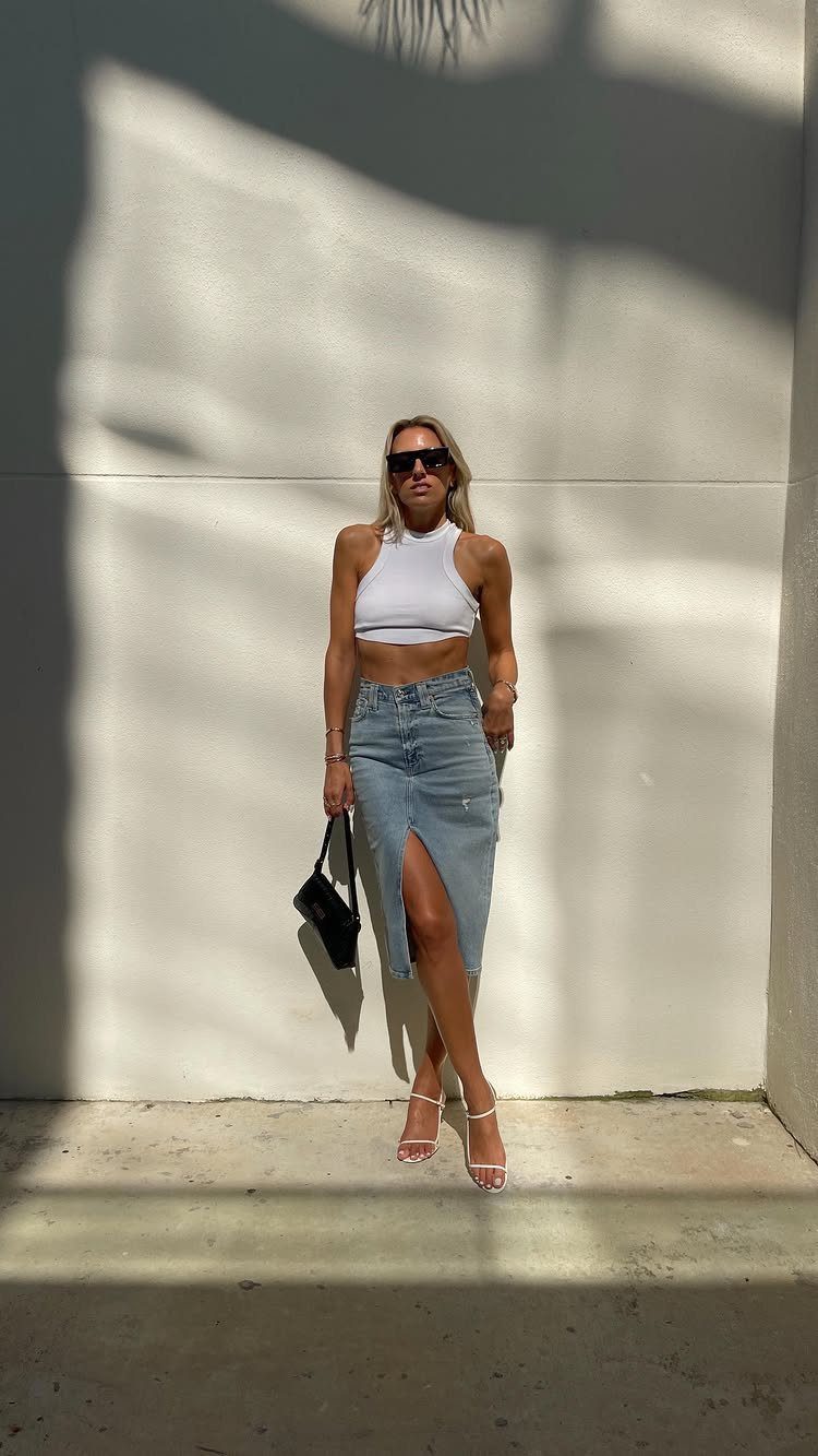 12 Midi Skirt Outfits for Every Season and Style 11 Woman in white crop top and denim midi skirt with high-heeled sandals.