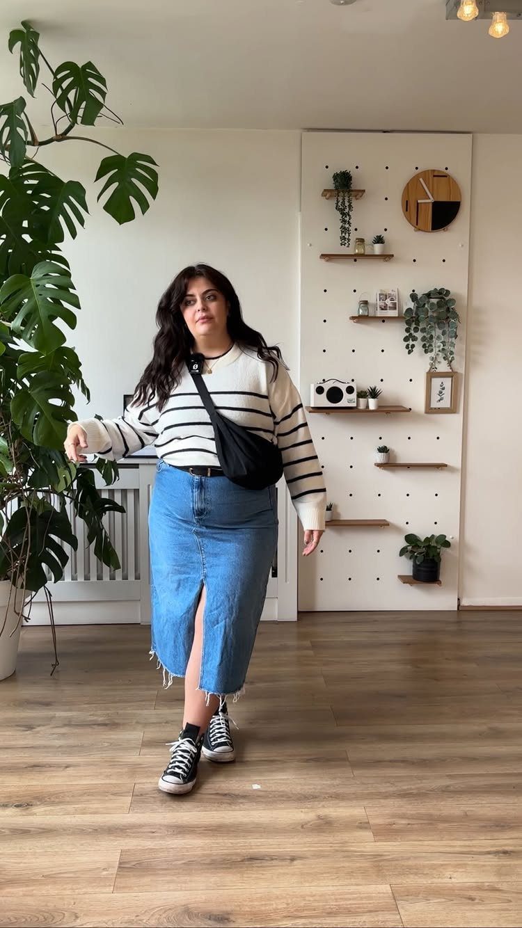 12 Midi Skirt Outfits for Every Season and Style 8 Woman wearing a striped top, denim midi skirt, and black sneakers in a room.