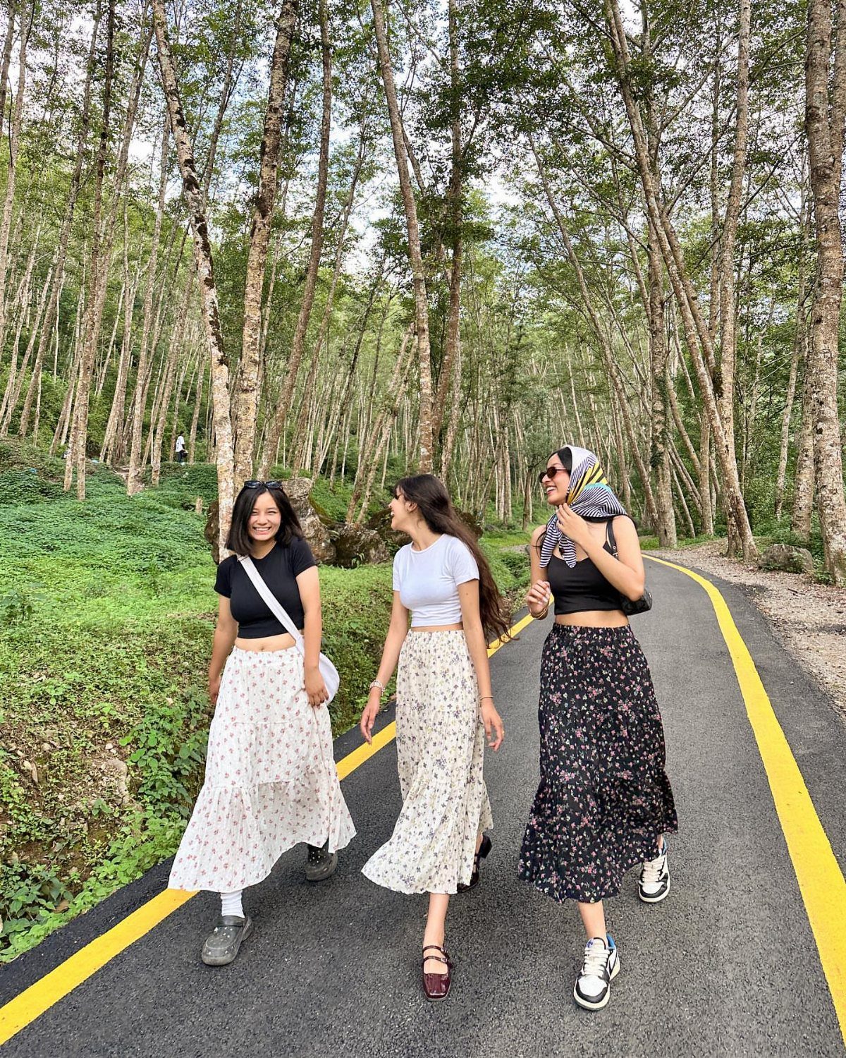 12 Midi Skirt Outfits for Every Season and Style 5 Three women wearing floral midi skirts and t-shirts walking on a forest road.
