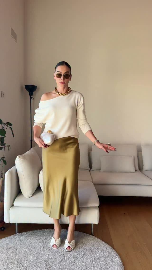 12 Midi Skirt Outfits for Every Season and Style 9 Woman in white off-shoulder knit top and gold satin midi skirt standing indoors.