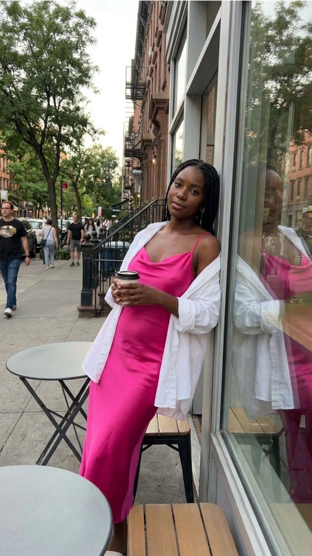 15 Millie Bobby Brown Outfits to Inspire Your Wardrobe 1 Woman wearing a bright pink satin slip dress and white shirt on a city street