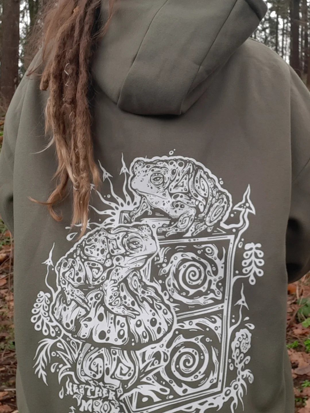 3 Modest Rave Outfits That Keep You Covered and Comfortable 3 Person with dreadlocks wearing an olive green hoodie with a white frog graphic.