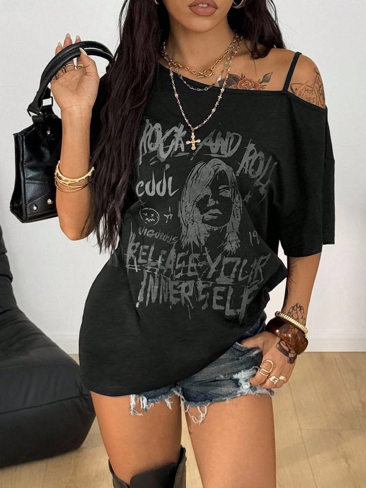 Off Shoulder Outfits: 8 Ideas from Casual to Dressed Up 4 Person wearing a black off-shoulder graphic t-shirt and distressed denim shorts.