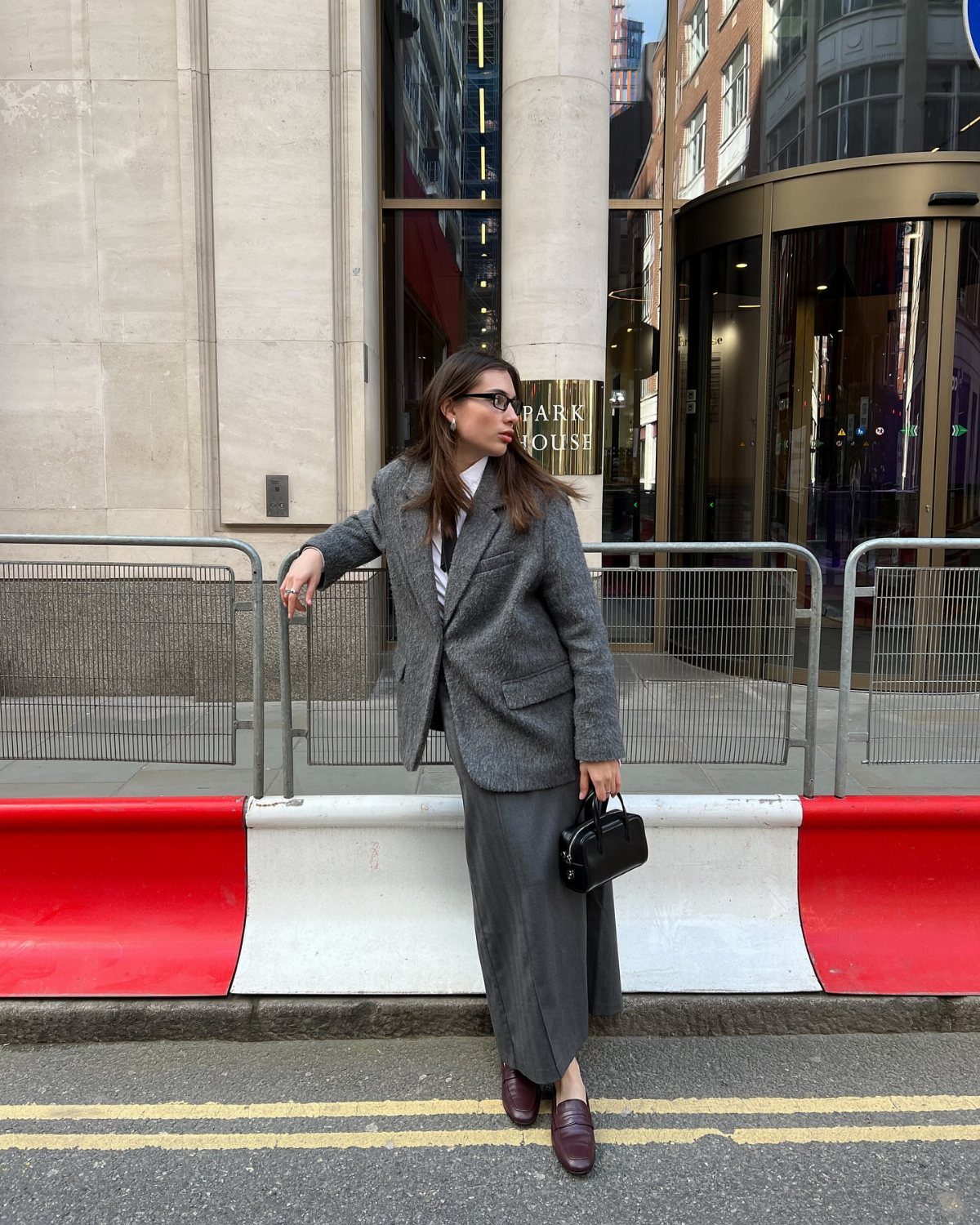 8 Office Siren Outfits to Master the Look in 2026 8 Woman in a grey oversized blazer and matching maxi skirt on a city street.