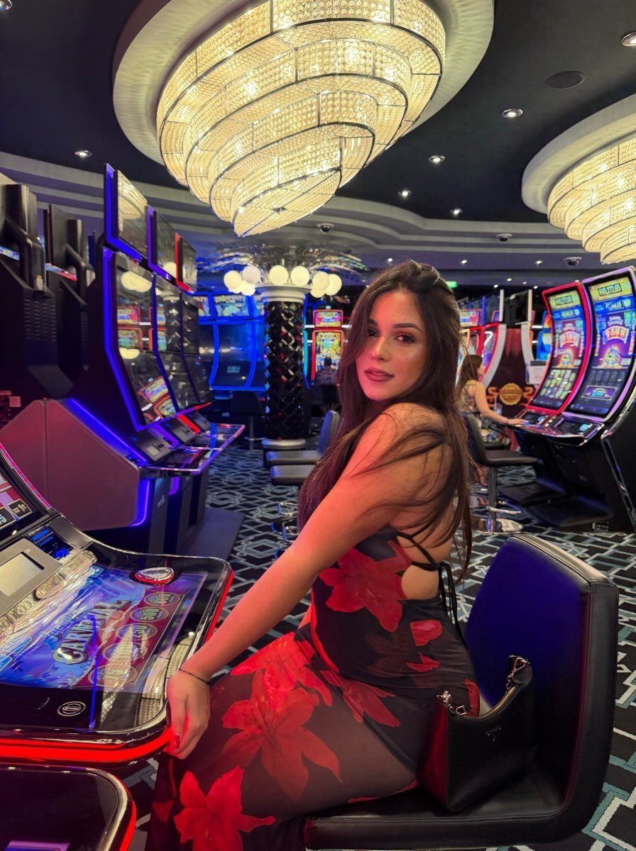 Woman in a red and black floral maxi dress sitting in a casino.