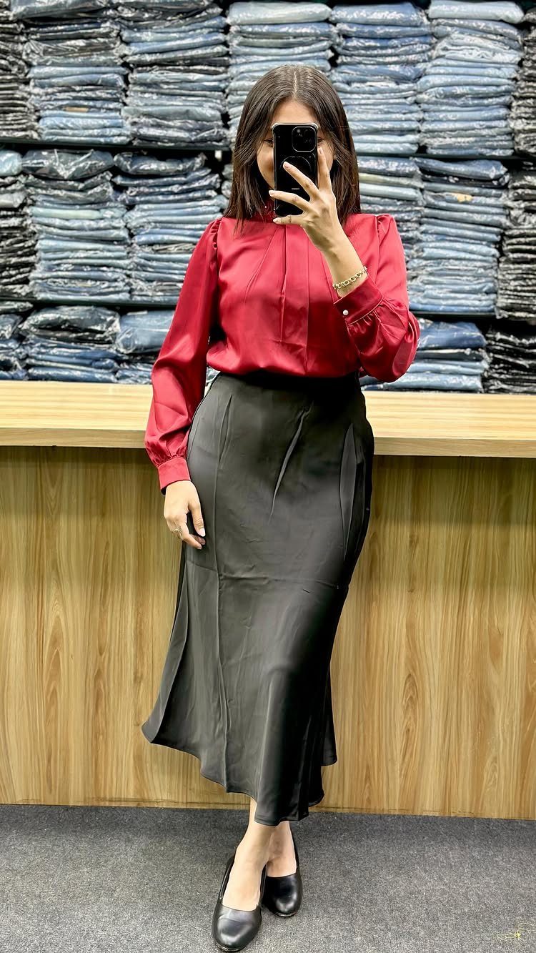 Woman wearing a red silk blouse and black pencil skirt with black heels.
