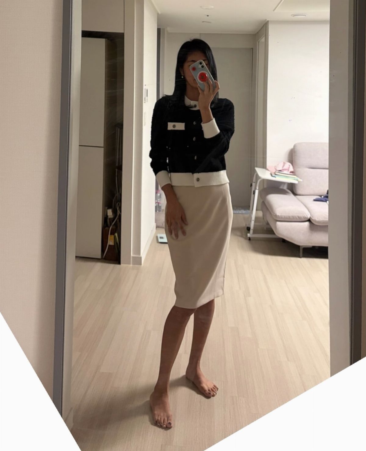 Woman wearing a black cropped cardigan and a cream high-waisted pencil skirt.