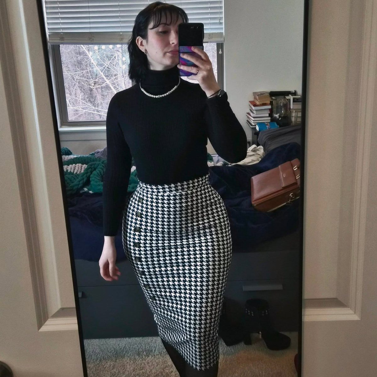 Person wearing a black turtleneck and a houndstooth pencil skirt in a mirror selfie