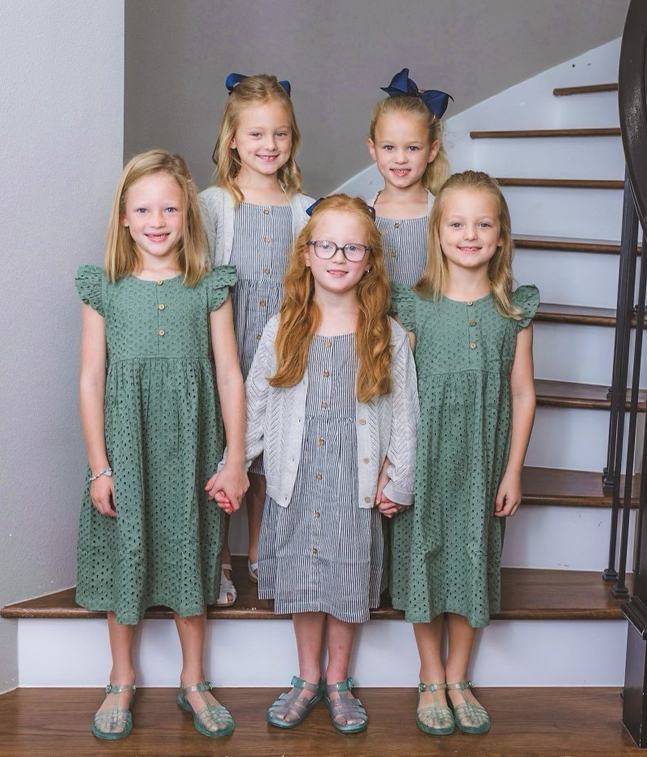Picture Day Outfits That Photograph Beautifully (7 Ideas) 5 Five young girls in coordinating green and striped dresses posing on wooden stairs.