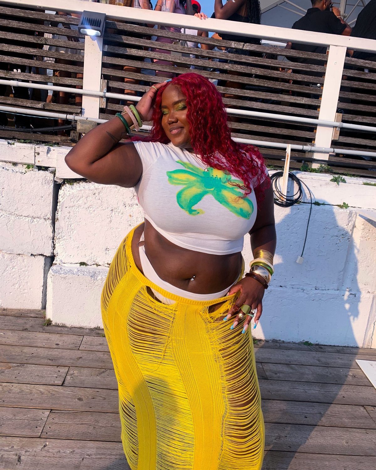 Plus Size Festival Outfits: 9 Looks You'll Want to Wear 9 Plus-size woman with red hair wearing a white crop top and yellow crochet skirt.
